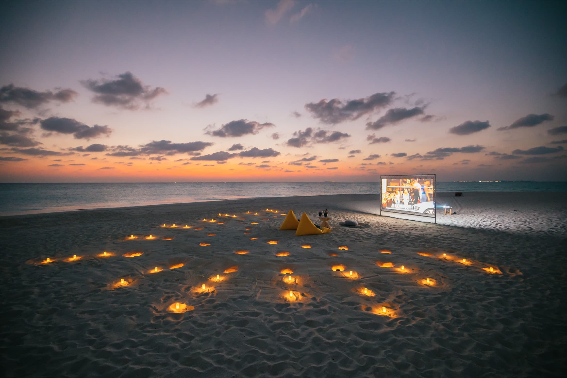 An open-air movie set up on the beach at dusk