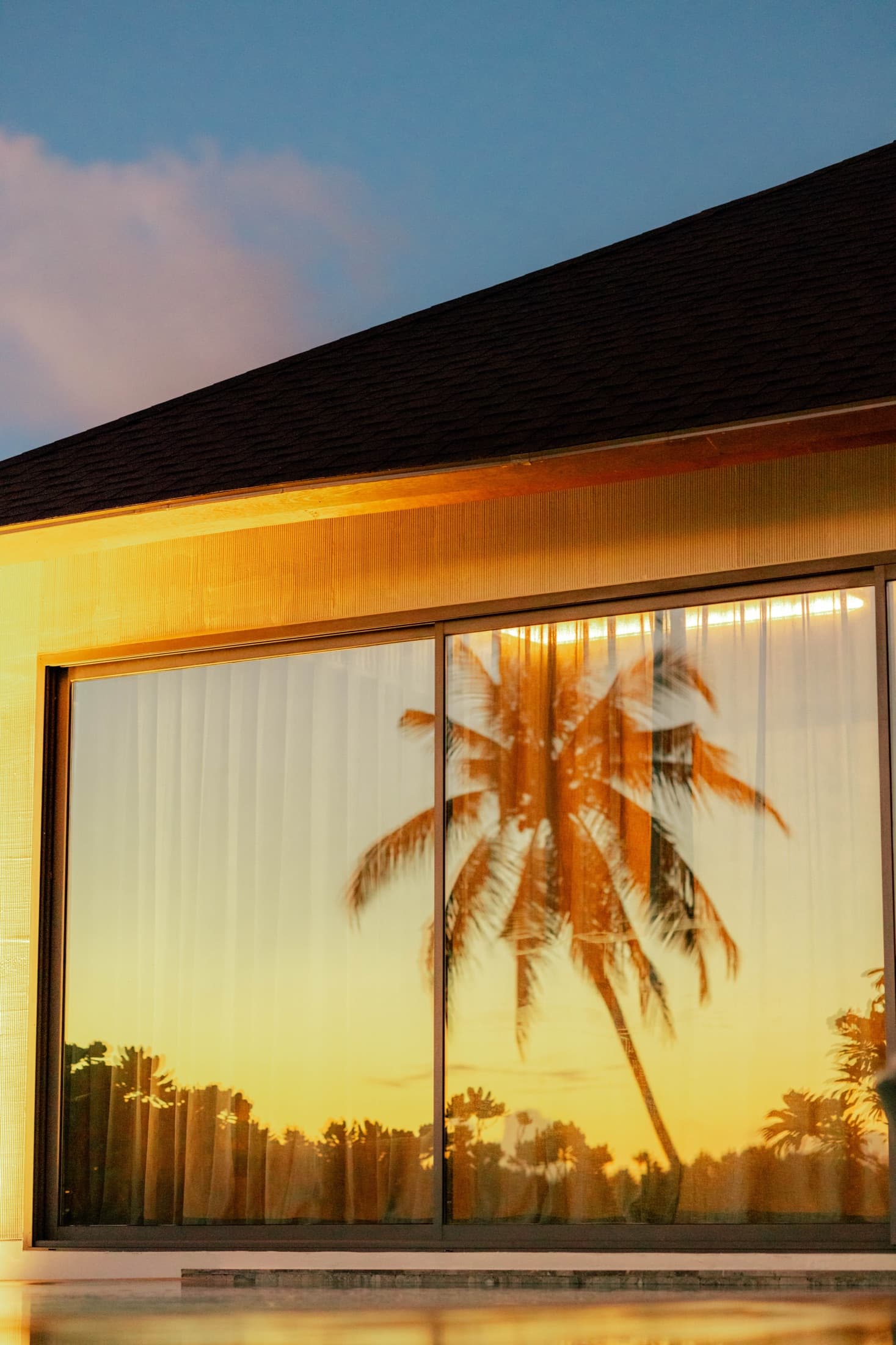 Sunset palms reflected in a villa's glass frontage